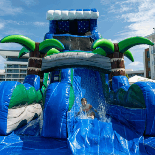 Image of a guest smiling while sliding down a large inflatable waters slide on Hammock Grove at Evermore Orlando Resort.