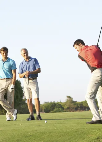 Group of guests golfing on Grand Cypress Golf course with two guests admiring in the distance as one guest is mid-swing