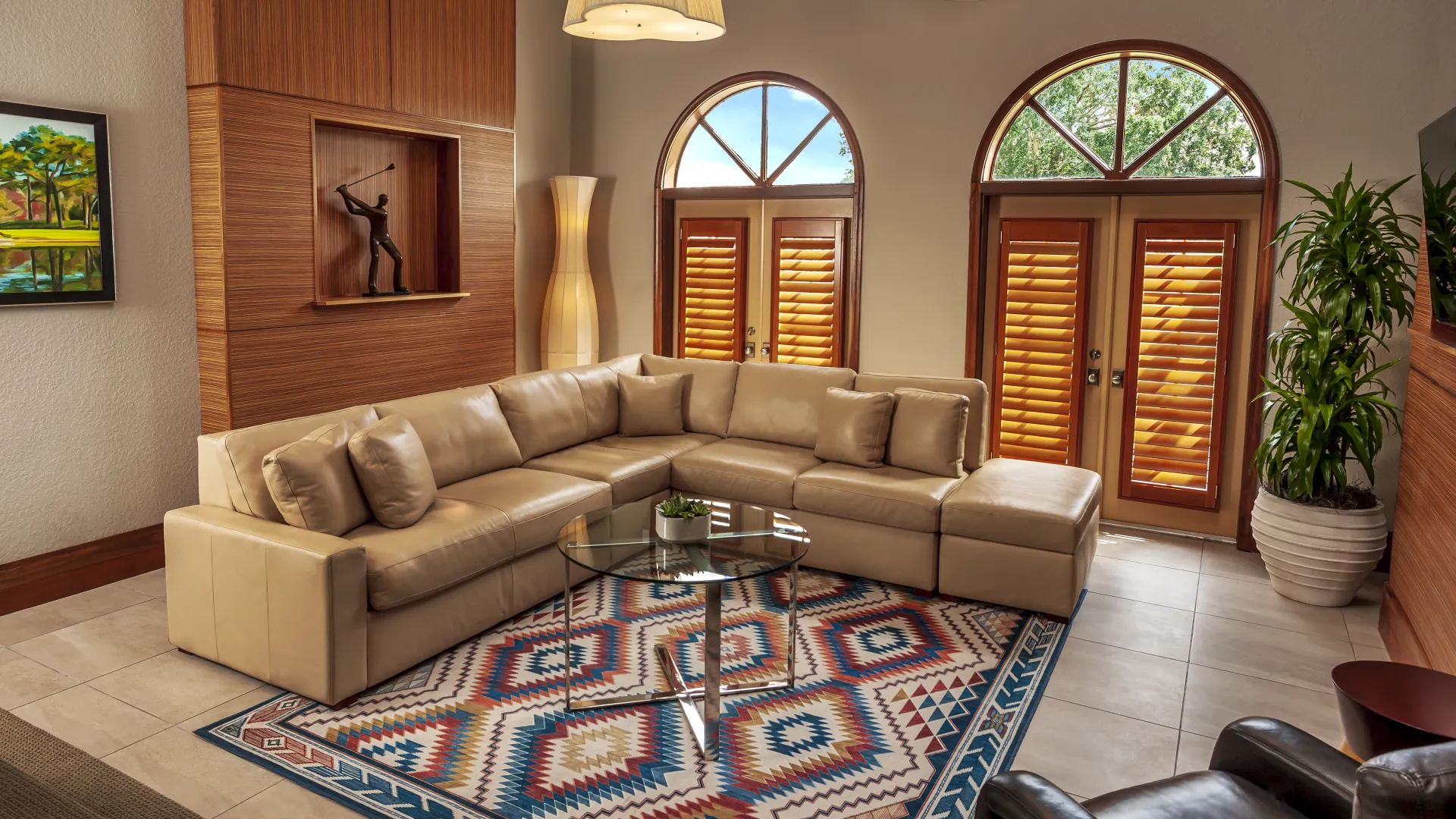 An image of the large living room inside of an Evermore Orlando Resort Villa. The oversized heart of the villa is anchored by a large sectional couch that faces a large wall-mounted tv with 2 sets of double doors that give easy access to the exterior patio and allow for abundant amounts of natural light into the villa.