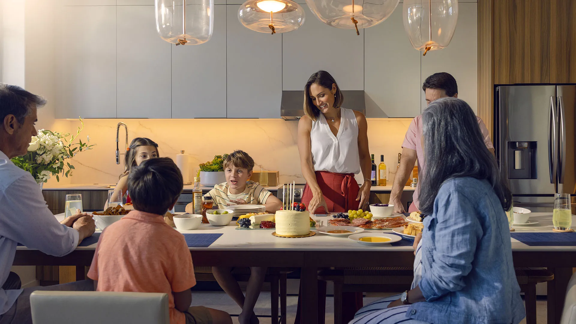An image of a family sitting around the dinner table enjoying a catered meal in a vacation rental house at Evermore Orlando Resort.