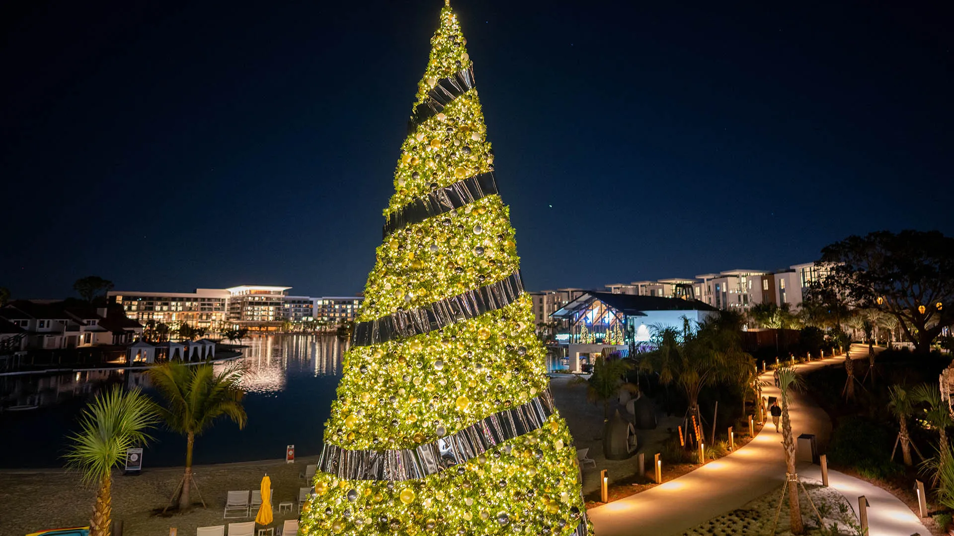 An image of a large Christmas tree by The Landing overlooking Evermore Bay at Evermore Orlando Resort.