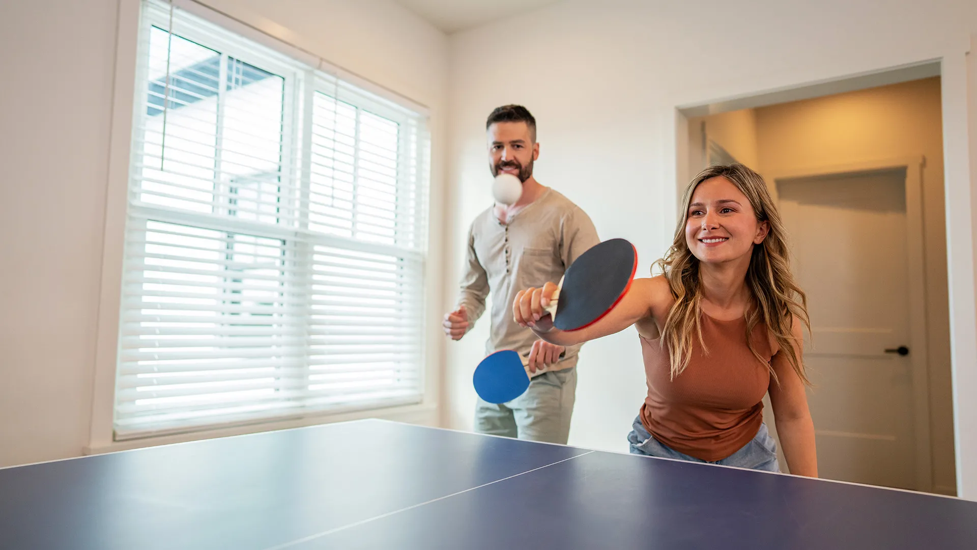 An image of guests having fun while playing ping pong inside their vacation House at Evermore Orlando Resort.