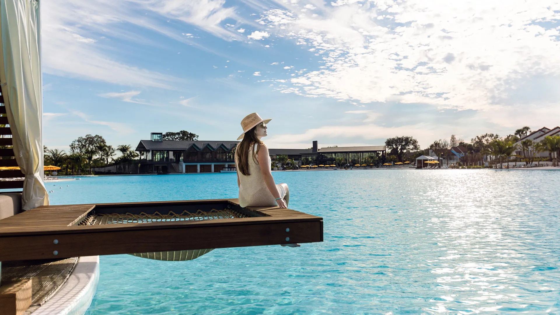 An image of a woman relaxing by the netting of the overwater hammock in a private cabana on Evermore Bay at Evermore Orlando Resort.