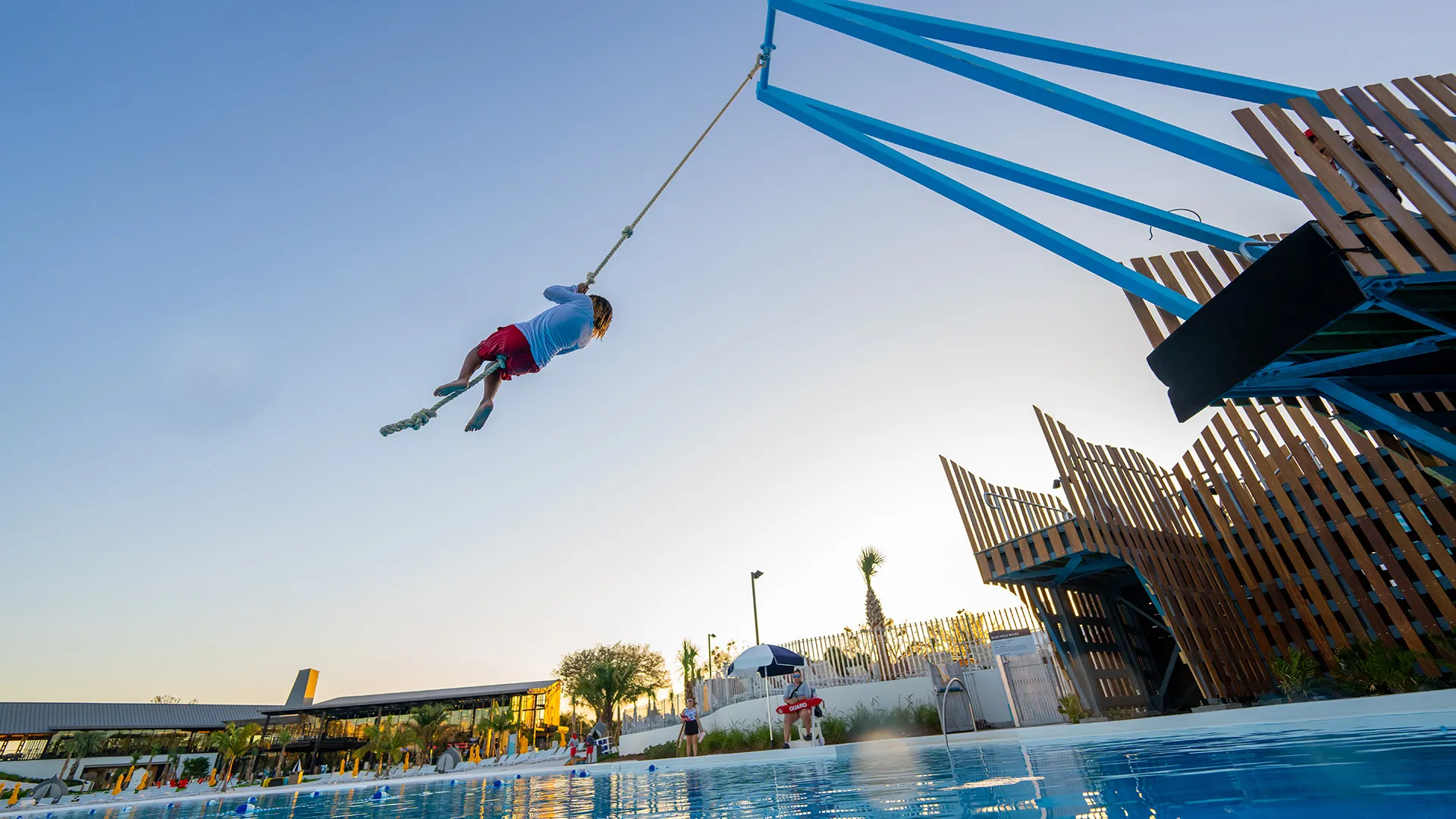 Image of a guest enjoying the thrill of the rope swing before jumping into Evermore Bay at Evermore Orlando Resort.