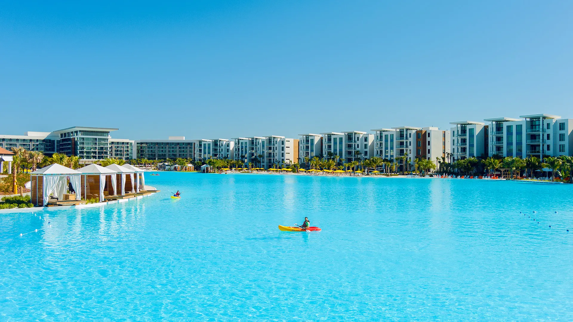 An image of Evermore Bay with Private Cabanas, Kayakers, Conrad Hotel and Evermore Flats in view.