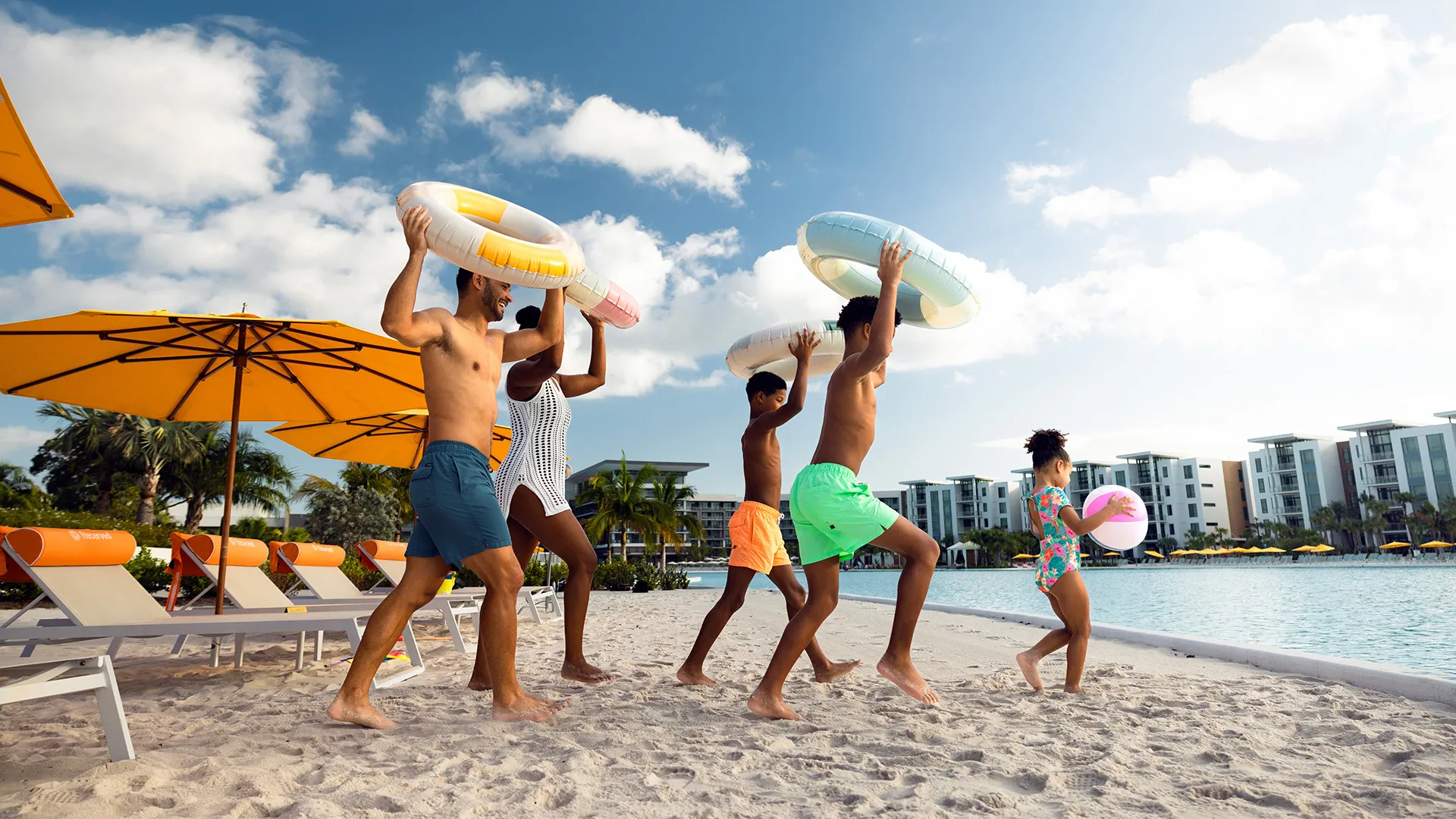 An image of a family entering Evermore Bay with beach balls and floatation devices.