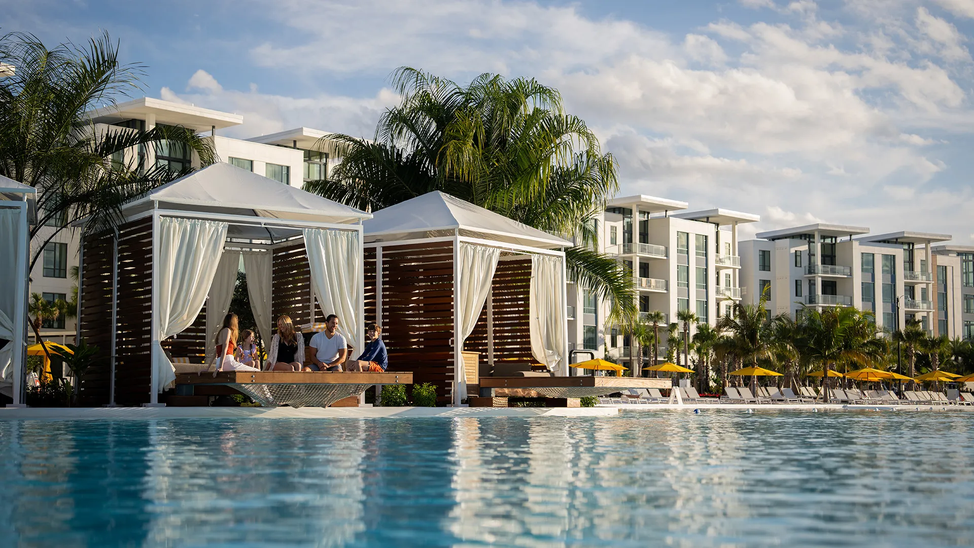 An image of a family sitting in a Private Cabana at Evermore Bay embracing one another.