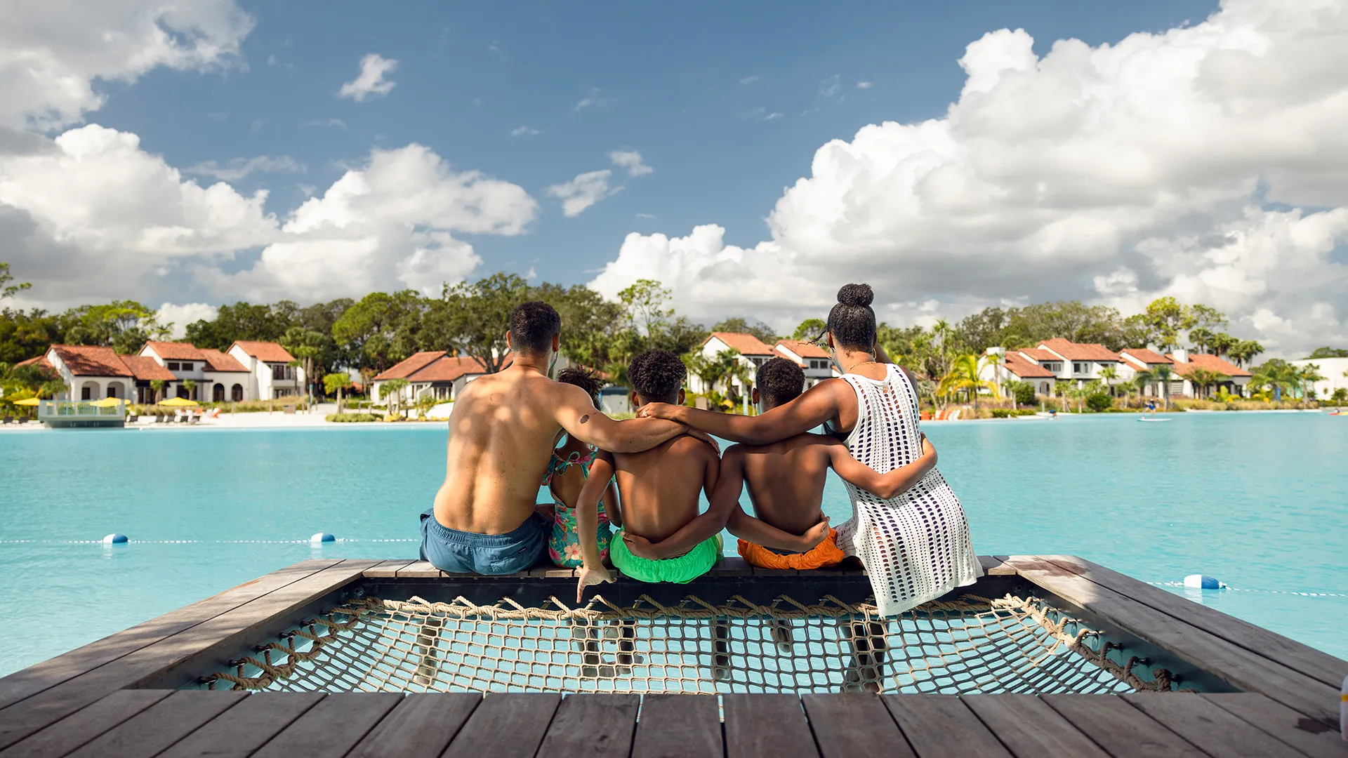 An image of a family sitting in a Private Cabana at Evermore Bay embracing one another.