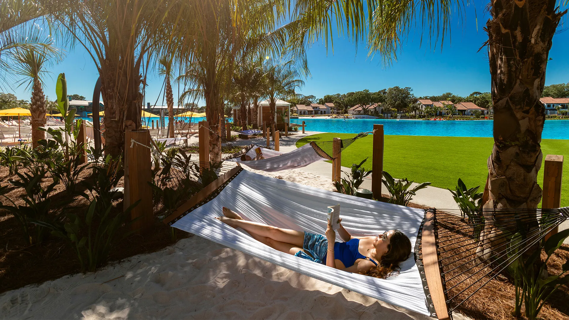 An image of a guest relaxing in a hammock in Hammock Grove with the view of Evermore Bay. 