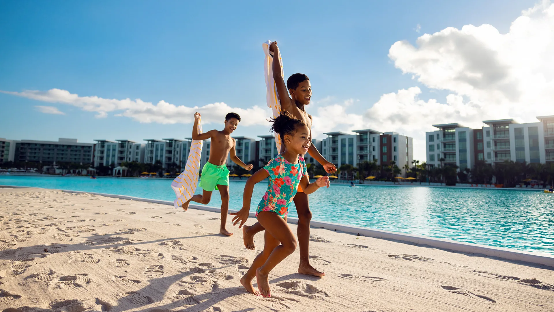 An image of kids running on beach alongside Evermore Bay with the Flats in the background.