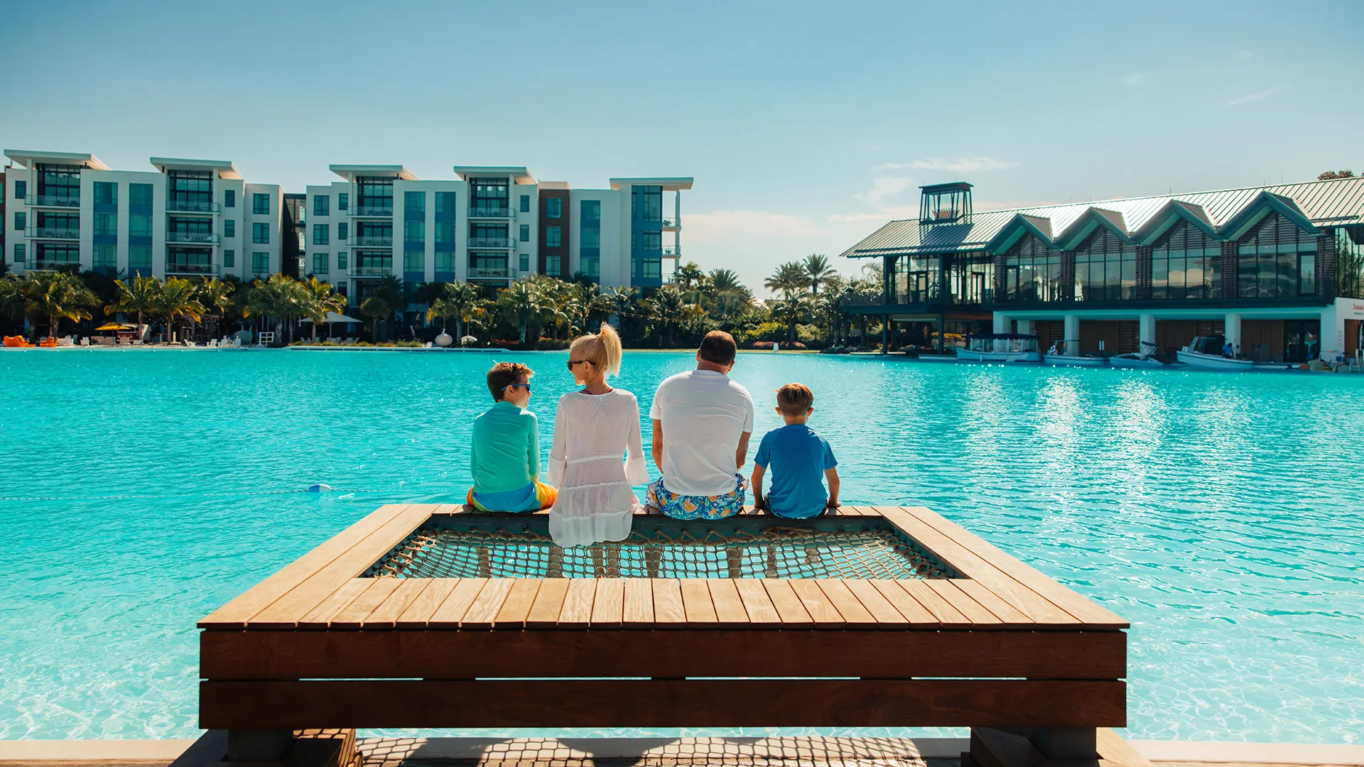 Image of a family relaxing on the overwater hammock at their private cabana on Evermore Bay at Evermore Orlando Resort.