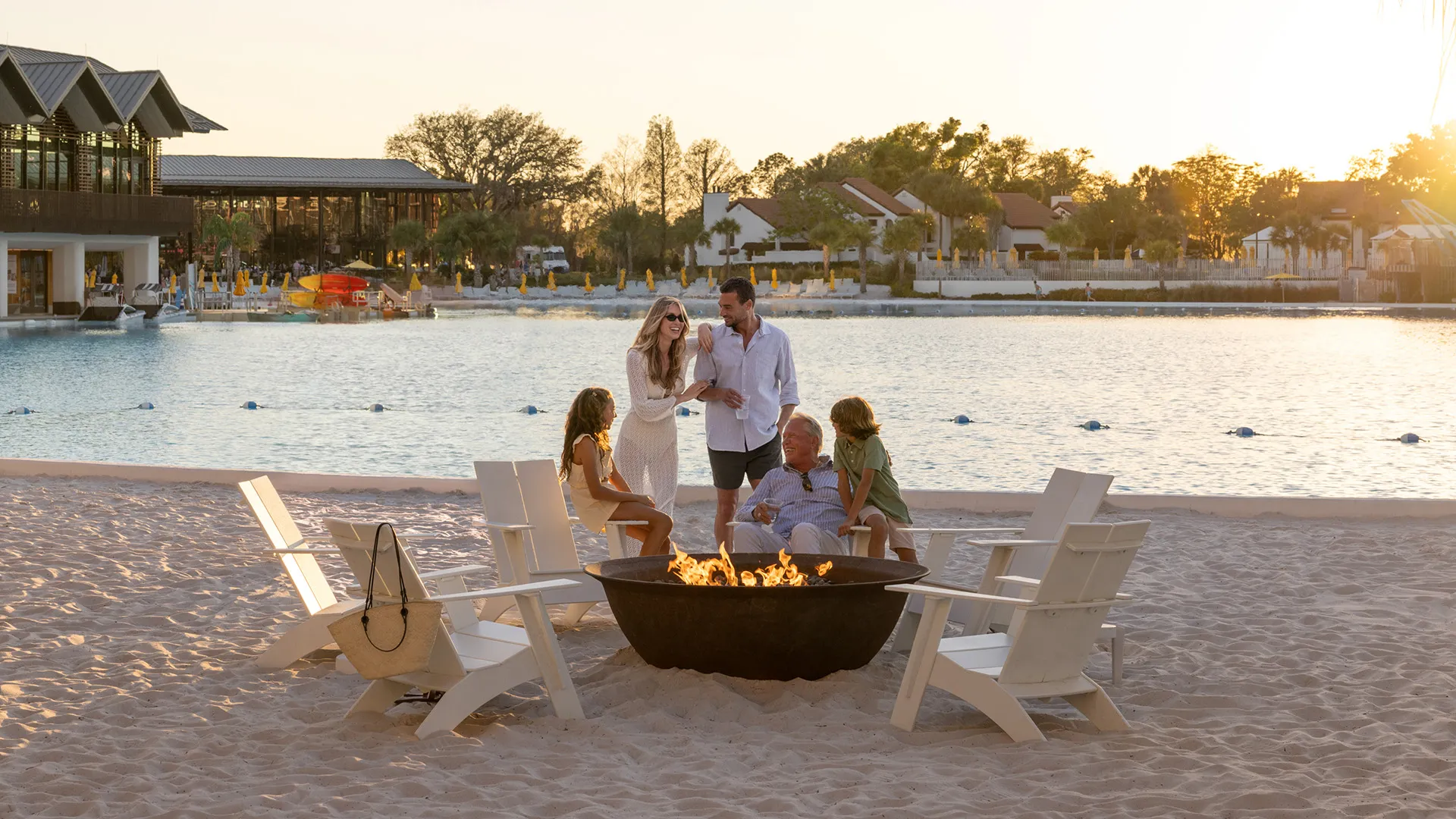 Image of a multi-generational family enjoying time together by a fire pit near Evermore Bay at Evermore Orlando Resort.