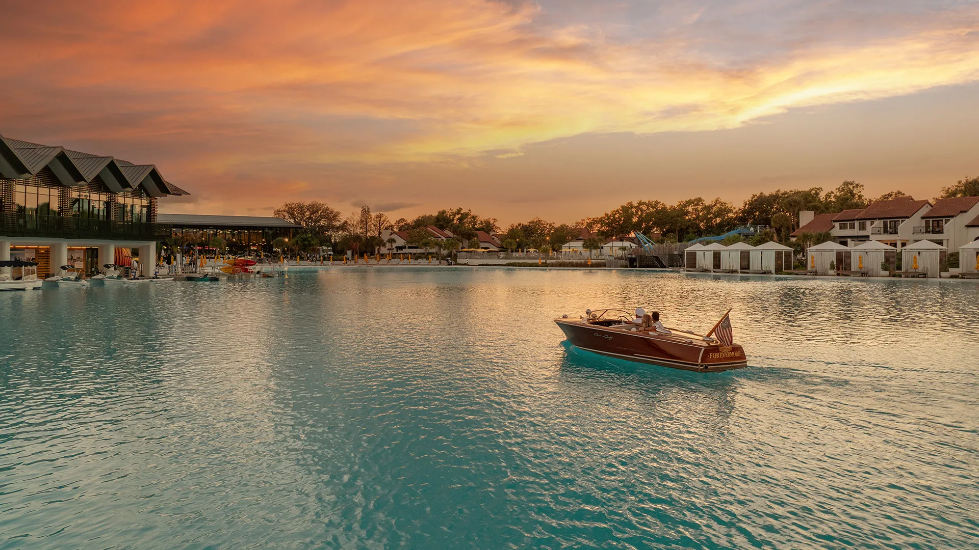 Image of a couple enjoying a cruise on the Chris-Craft boat as the sun sets over Evermore Bay at Evermore Orlando Resort.