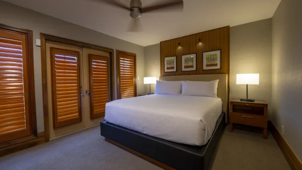 An image of an Evermore Orlando Resort Villa bedroom featuring a plush king-sized bed and a set of doors that lead out to an exterior patio..