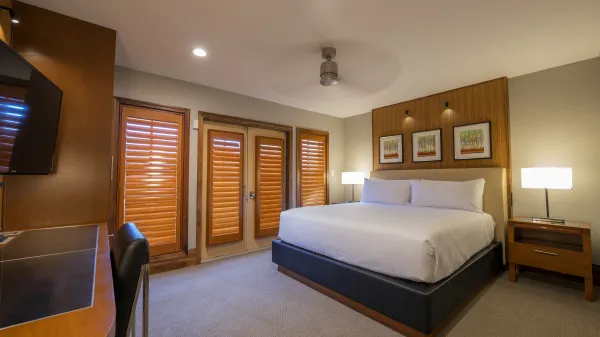 An image of an Evermore Orlando Resort Villa bedroom featuring a plush king-sized bed, a desk workspace and a wall-mounted television.