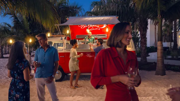 Image of guests having conversation while enjoying beverages on the beach by Barbara Ann's Beach Bar at Evermore Orlando Resort.