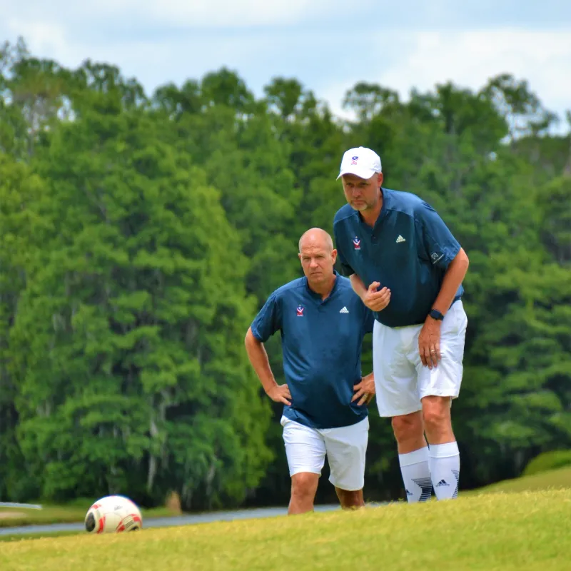 Two men playing footgolf Two caucasian men looking at a soccer ball