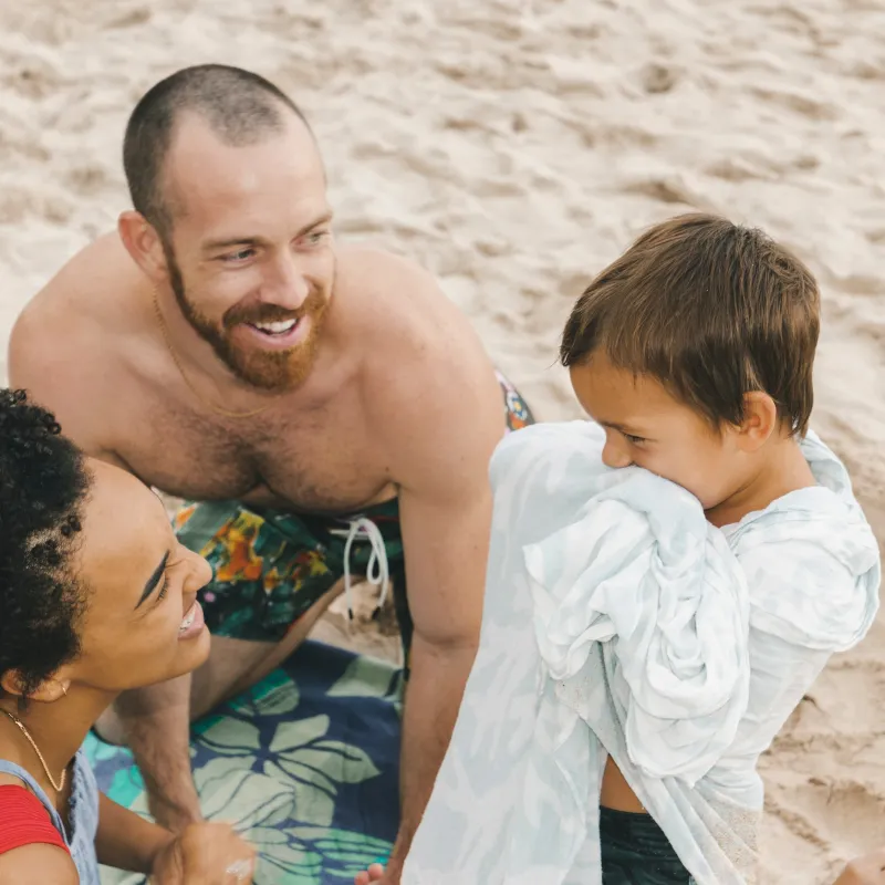 Incentive Trip Family Mother and father with child in towel on shore of Evermore Bay