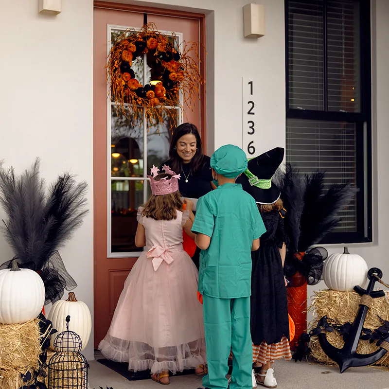 An image of kids dressed in Halloween costumes trick-or-treating at a house at Evermore Orlando Resort.