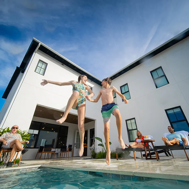 An image of two kids jumping into a private pool at their vacation house at Evermore Orlando Resort.