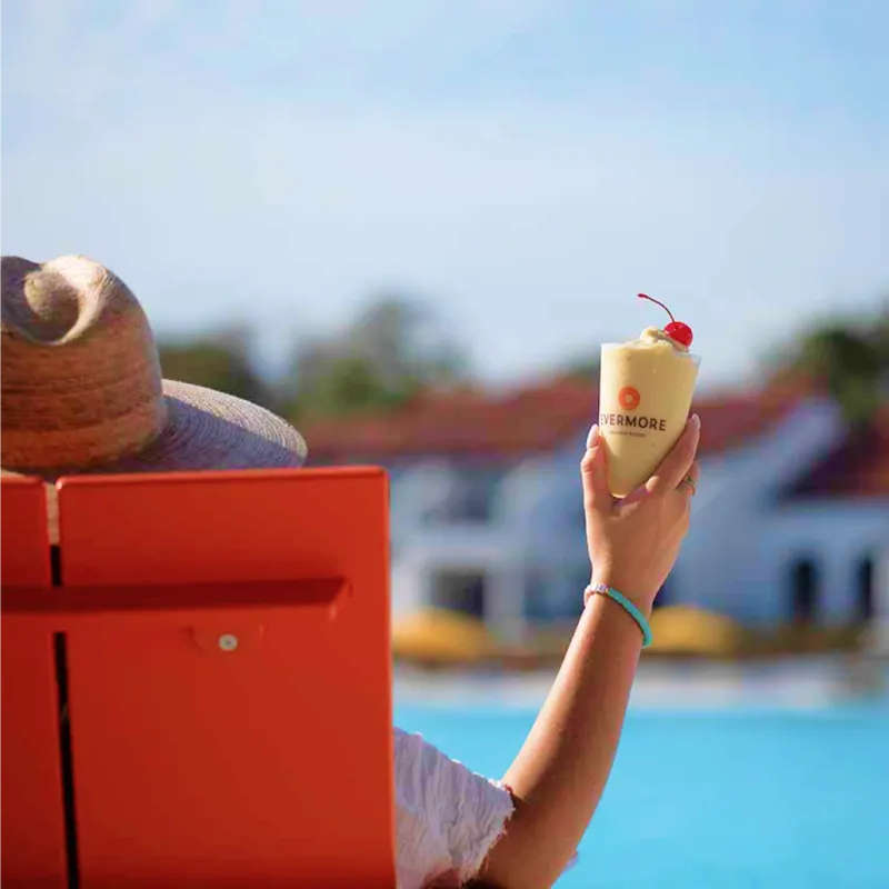 An image of a person in a beach chair with frozen drink in hand relaxing by Evermore Bay at Evermore Orlando Resort.