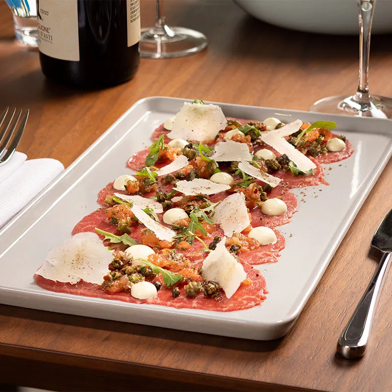 An image of the Beef Carpaccio dish on a table in Sophia's Trattoria in Conrad Orlando at Evermore Orlando Resort.
