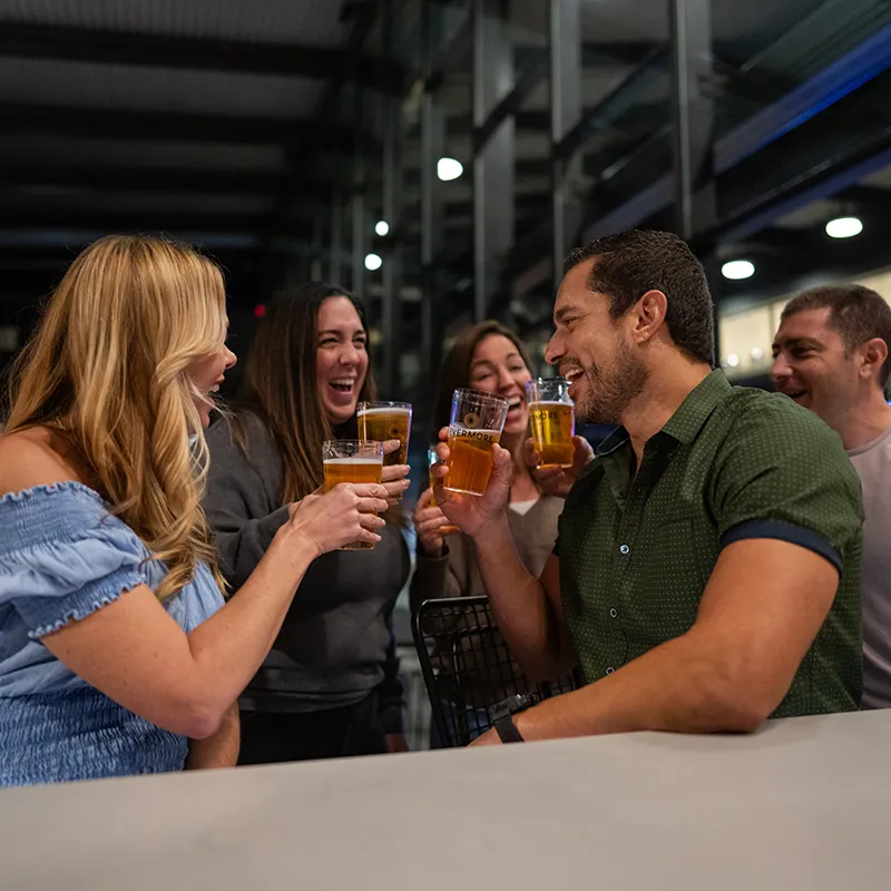 An image of guests enjoying beers at ebb + flow Bar in The Landing at Evermore Orlando Resort.