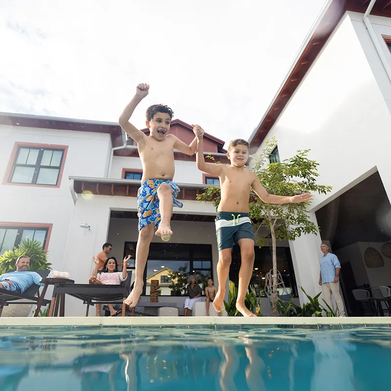 An image of two kids jumping into a private heated pool at a vacation rental house at Evermore Orlando Resort.