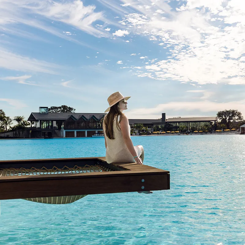 An image of a woman relaxing by the netting of the overwater hammock in a private cabana on Evermore Bay at Evermore Orlando Resort.