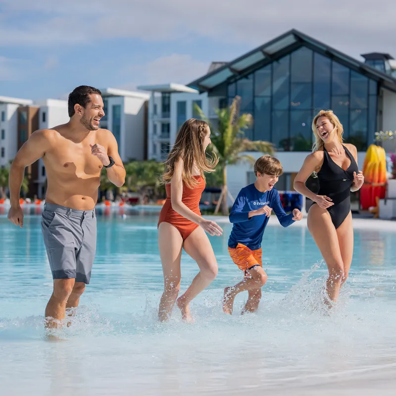 Family in Evermore Bay Image of a family laughing while walking onto South Beach from Evermore Bay at Evermore Orlando Resort.