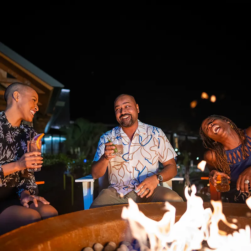 Guests Enjoying a Fire Pit by Evermore Bay Image of adult guests enjoying conversation and drinks while sitting next to a fire pit by Evermore Bay at Evermore Orlando Resort.