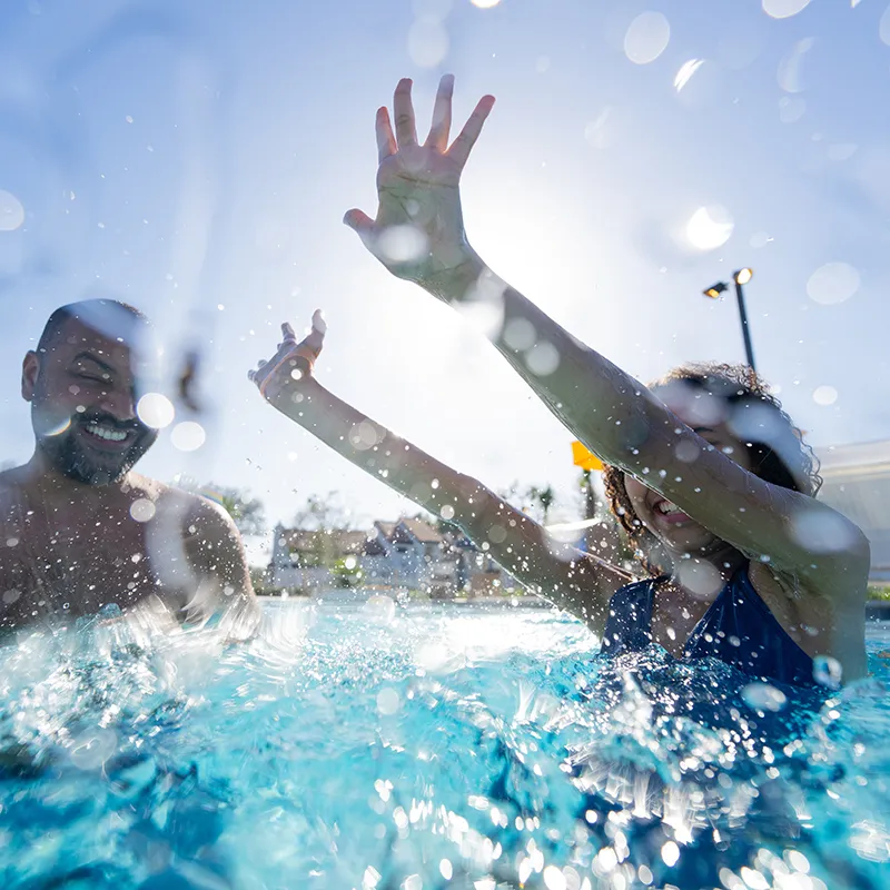 Image of a father and daughter smiling while playing together in a heated pool at Evermore Orlando Resort.