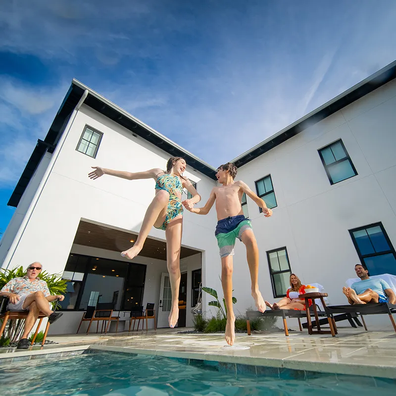 Image of kids jumping into the private heated pool in the backyard of a vacation home at Evermore Orlando Resort.