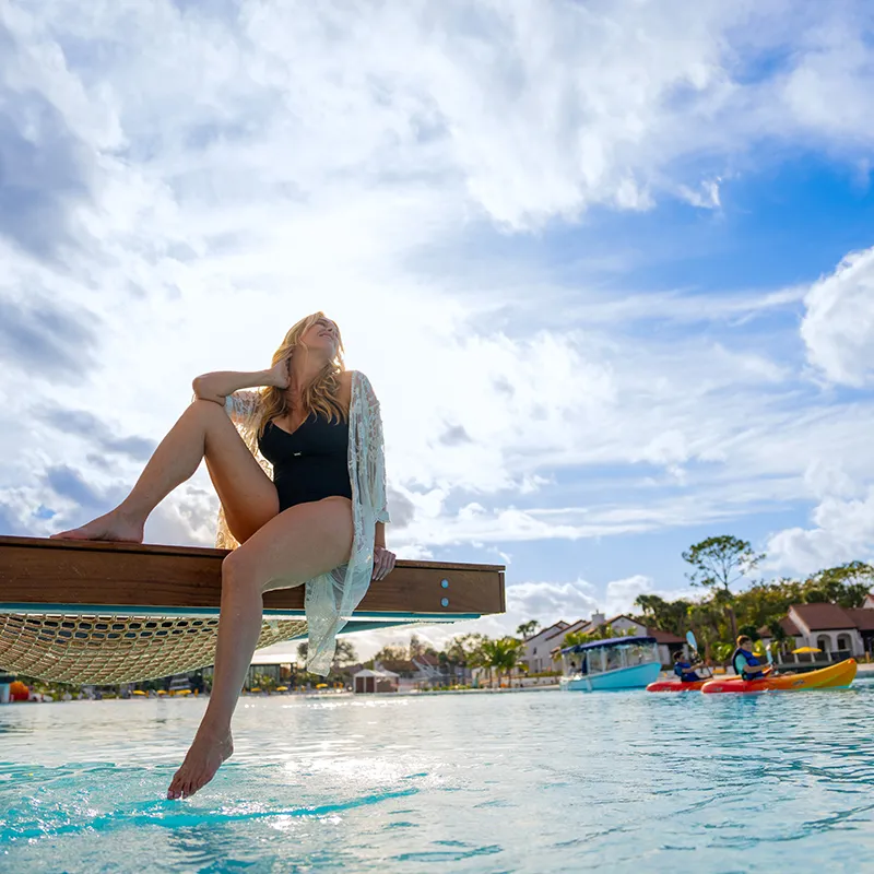 Image of a guest relaxing by the hammock of a luxury Overwater Cabana on Evermore Bay at Evermore Orlando Resort.