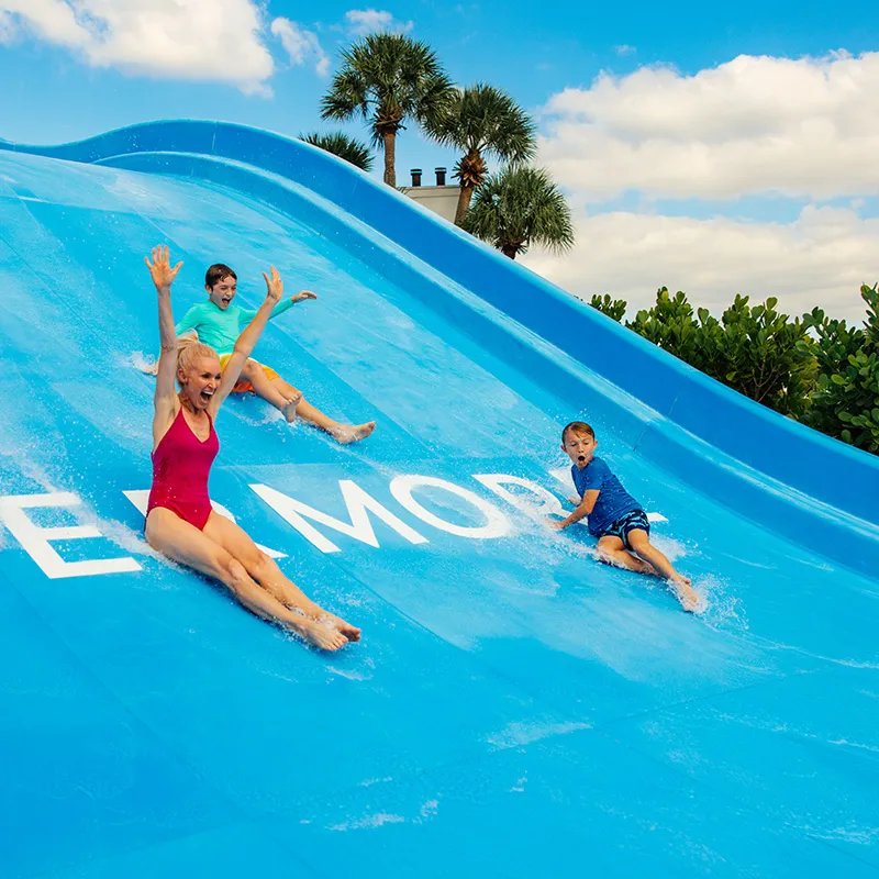 Image of a family laughing while sliding down the 4-person waterslide at the Family Waterslide Pool at Evermore Orlando Resort.
