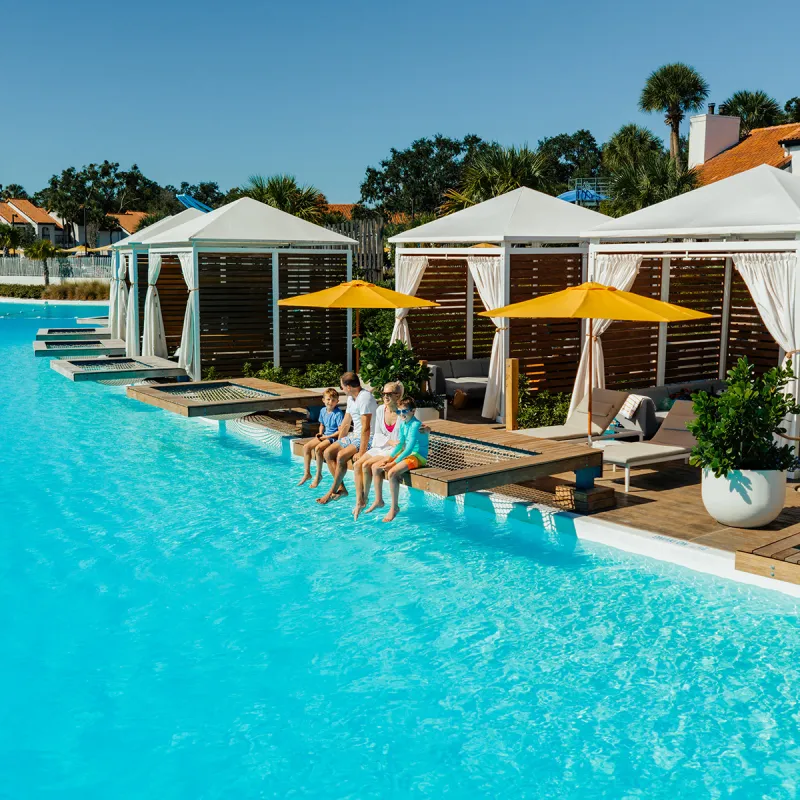 Image of a family relaxing on the overwater hammock at their private cabana on Evermore Bay at Evermore Orlando Resort.