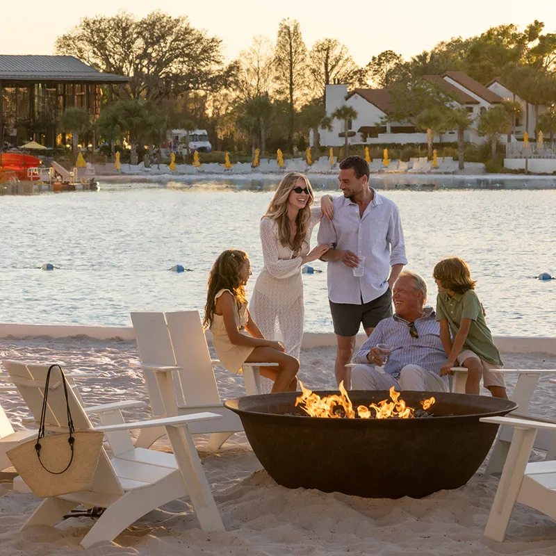 Image of a multi-generational family enjoying time together by a fire pit near Evermore Bay at Evermore Orlando Resort.