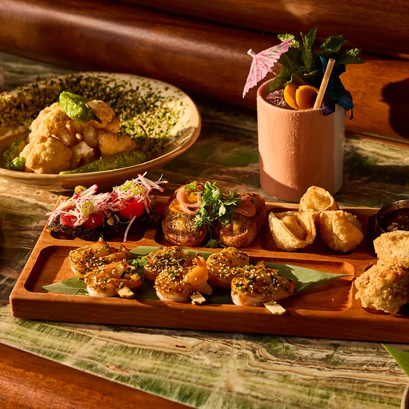 Image of the Pu Pu Platter dish with a craft cocktail from Papaya Club in Conrad Orlando at Evermore Orlando Resort.