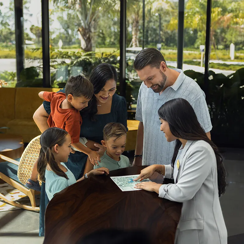 Image of a family talking with a Guest Services Host inside The Landing at Evermore Orlando Resort.