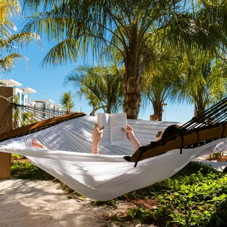 An image of a woman reading a book while relaxing in a hammock in Hammock Grove at Evermore Orlando Resort.