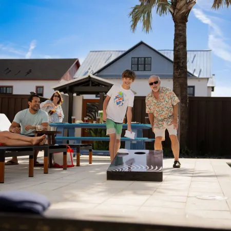 An image of a family playing cornhole and enjoying the private backyard of a vacation house at Evermore Orlando Resort.