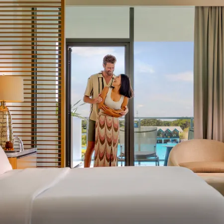 An image of a couple in a Conrad Orlando Suite with Evermore Bay in the background at Evermore Orlando Resort.