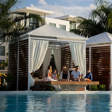 Family in Luxury Overwater Cabana Image of a family laughing while relaxing in the hammock of their luxury Overwater Cabana on Evermore Bay at Evermore Orlando Resort.
