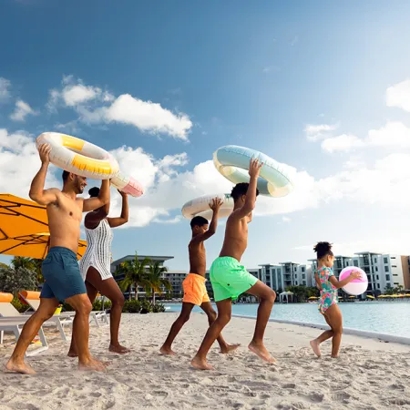 An image of a family entering Evermore Bay with beach balls and floatation devices.