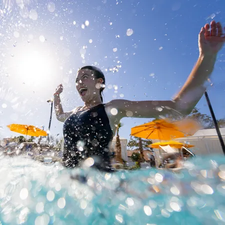 Image of a woman smiling while jumping into a pool at Evermore Orlando Resort.