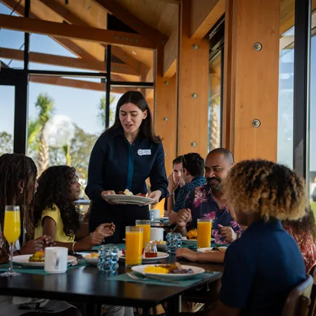 Image of a family enjoying time together while being served breakfast in Twin View Restaurant and Bar at Evermore Orlando Resort.